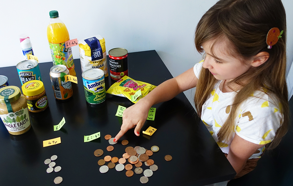 A young girl counts change and compares the prices of supermarket items