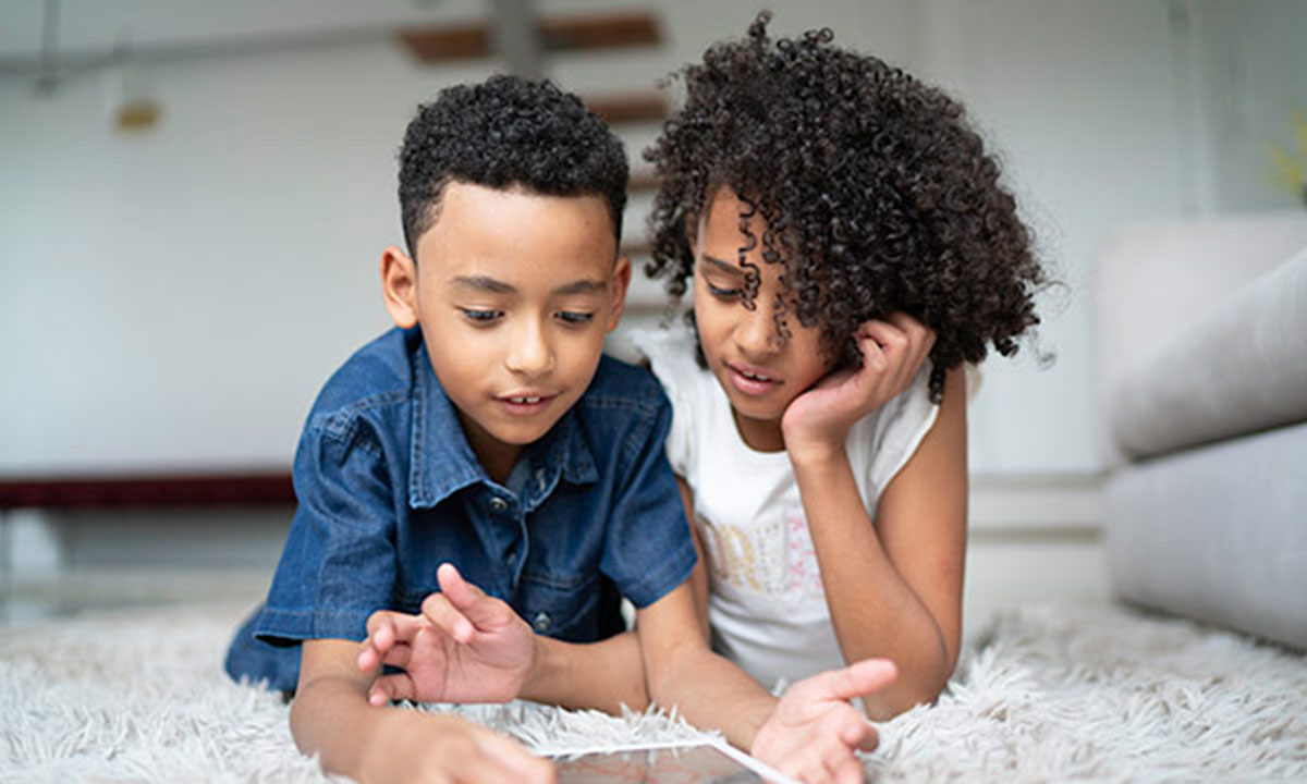 Two children play together on an iPad