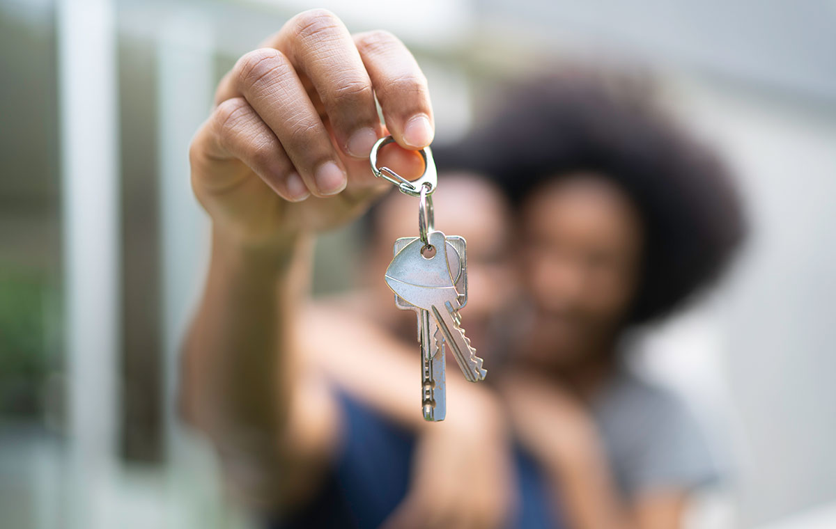 Happy homeowners hold up keys to their new home