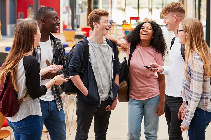 A group of university students stand around chatting and laughing