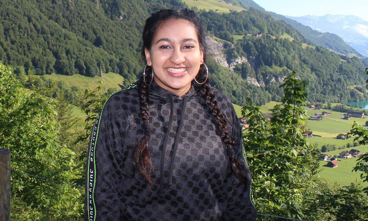 University student Khushi Jain, smiling at the camera with a beautiful green landscape behind her