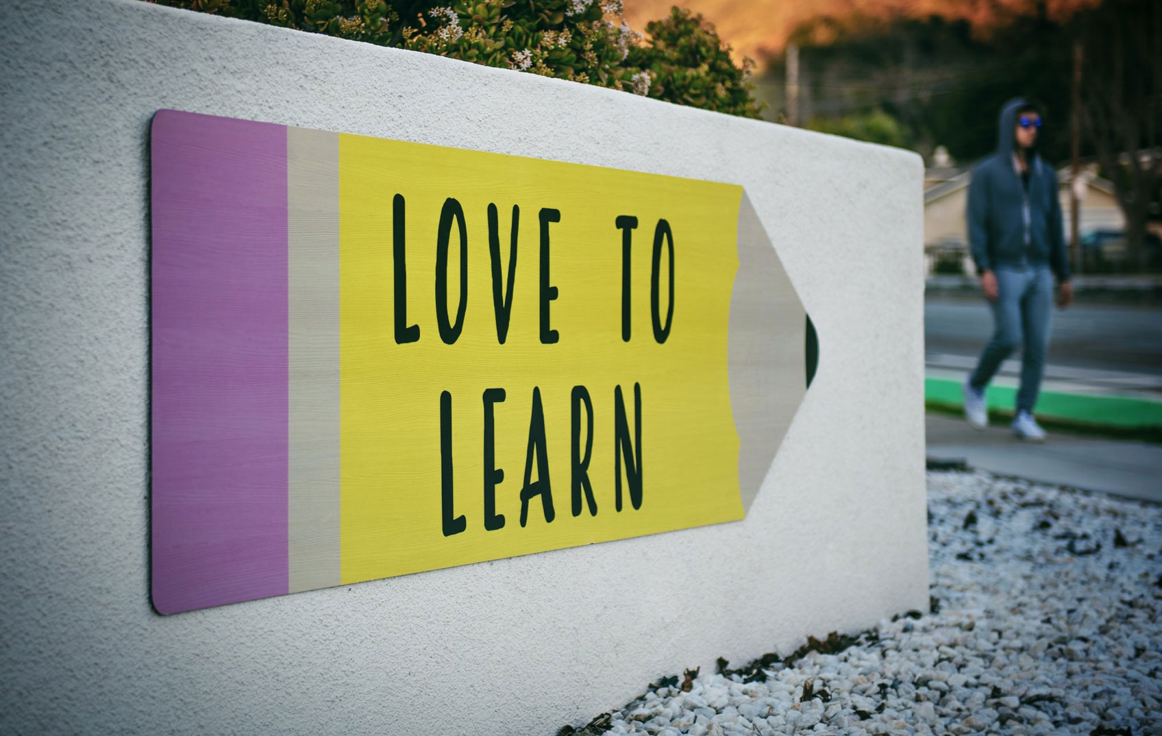 An outdoor sign in the shape of a pencil with the words 'LOVE TO LEARN' written on it
